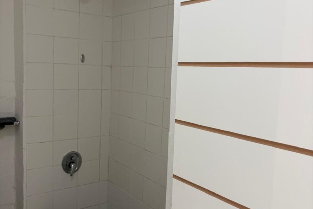 A functional bathroom shower area featuring a tiled enclosure, brick curb, and standard shower fixtures.