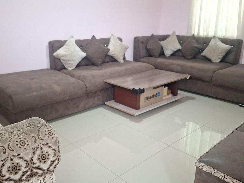A living room area featuring light-colored tiled flooring and neutral wall finishes, providing a functional space for relaxation.