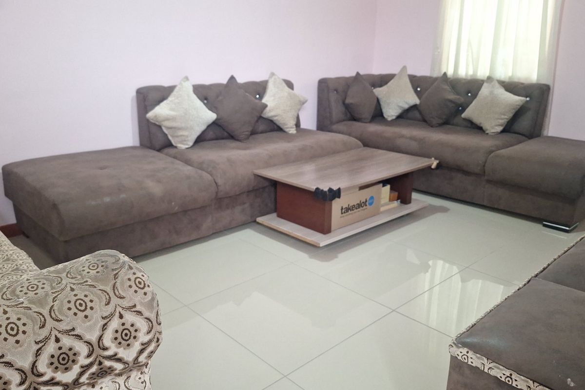 A living room area featuring light-colored tiled flooring and neutral wall finishes, providing a functional space for relaxation.