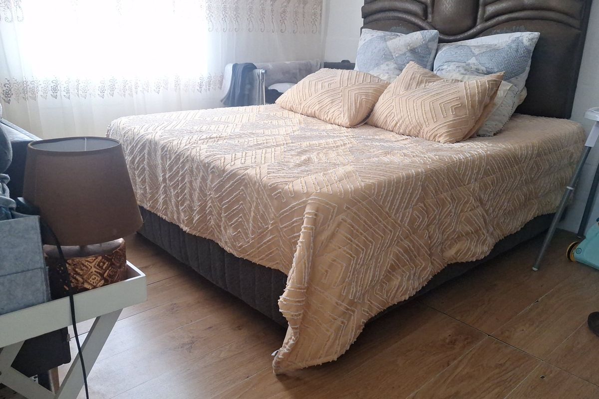 A bedroom featuring laminate flooring and a large bed, offering a functional space with natural light.