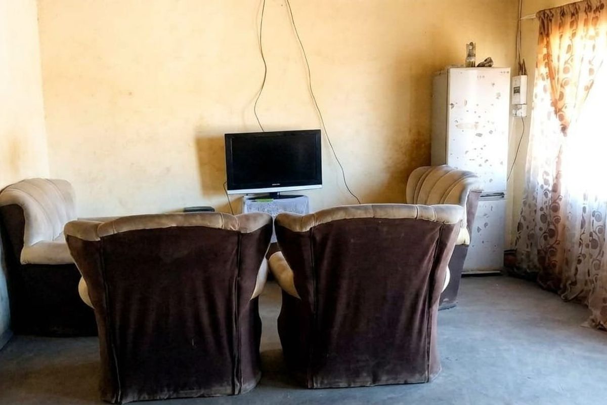 A living room area featuring plain wall finishes and basic electrical infrastructure, requiring cosmetic updates to improve the overall aesthetic and condition.