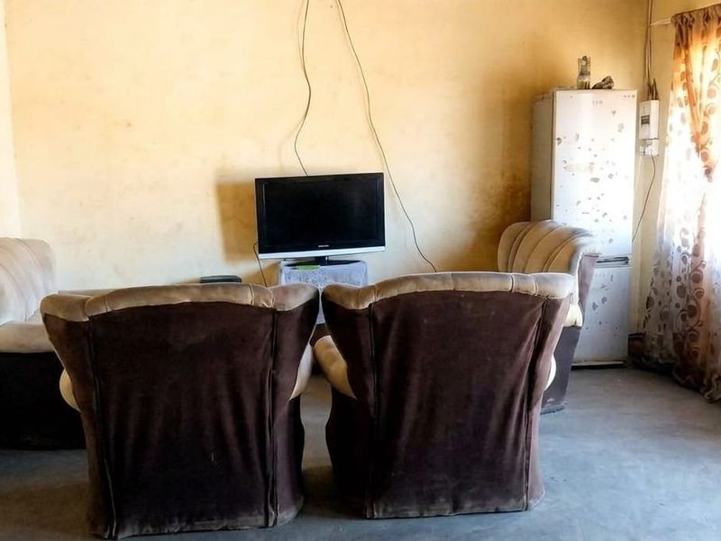 A living room area featuring plain wall finishes and basic electrical infrastructure, requiring cosmetic updates to improve the overall aesthetic and condition.