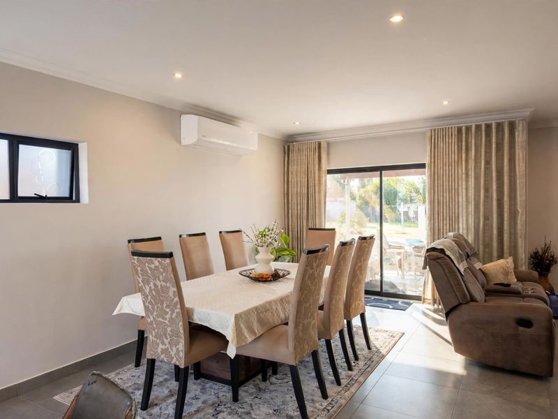 An open-plan dining area featuring tiled flooring, recessed lighting, a wall-mounted air conditioner, and large sliding glass doors providing access to the outdoor space.