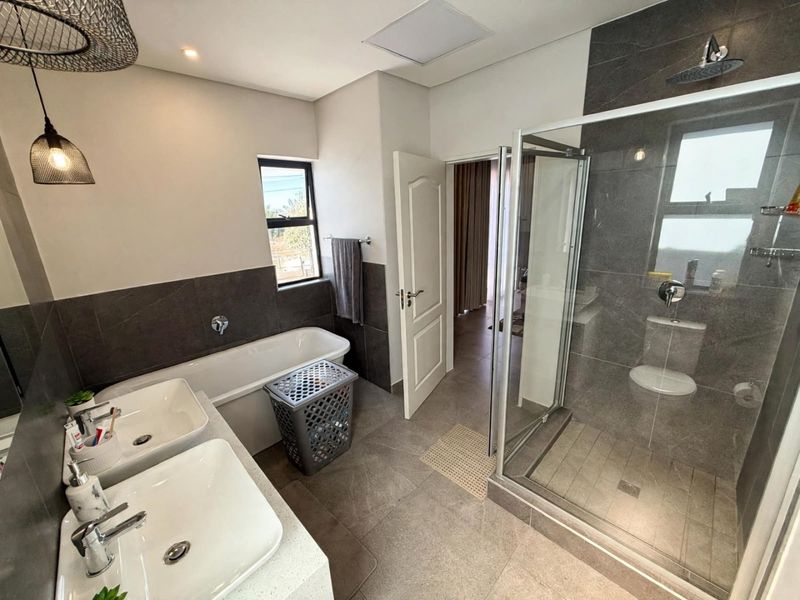 Modern bathroom featuring a double vanity, a sleek freestanding bathtub, and a spacious walk-in shower with contemporary grey tiling.