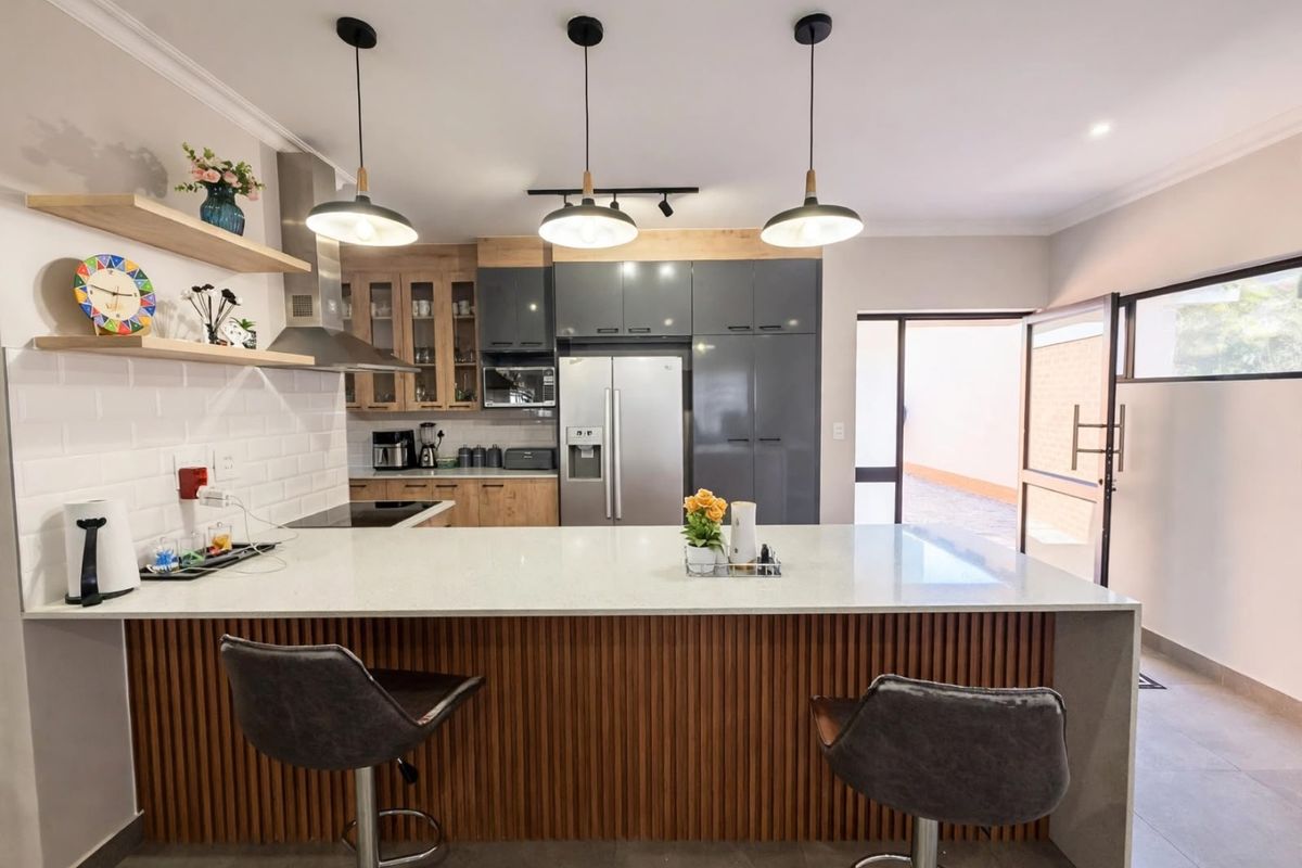 Modern kitchen featuring a large island with quartz countertops, sleek two-tone cabinetry, subway tile backsplash, and stylish pendant lighting.