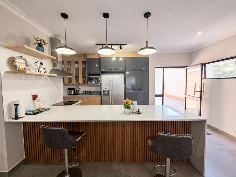 Modern kitchen featuring a large island with quartz countertops, sleek two-tone cabinetry, subway tile backsplash, and stylish pendant lighting.
