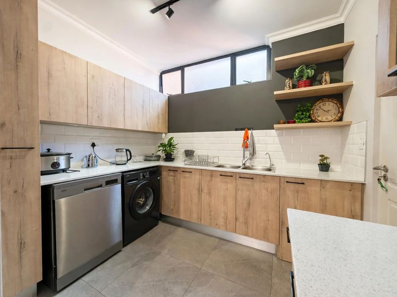 Modern scullery featuring light wood cabinetry, stone countertops, subway tile backsplash, and integrated space for laundry and dishwashing appliances.