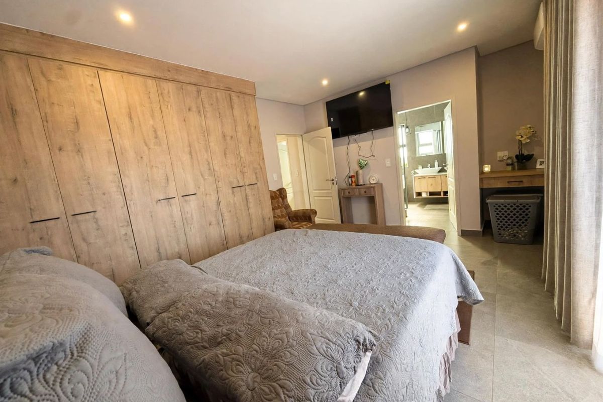 Spacious bedroom featuring extensive built-in wooden cabinetry, tiled flooring, recessed lighting, and direct access to an en-suite bathroom.