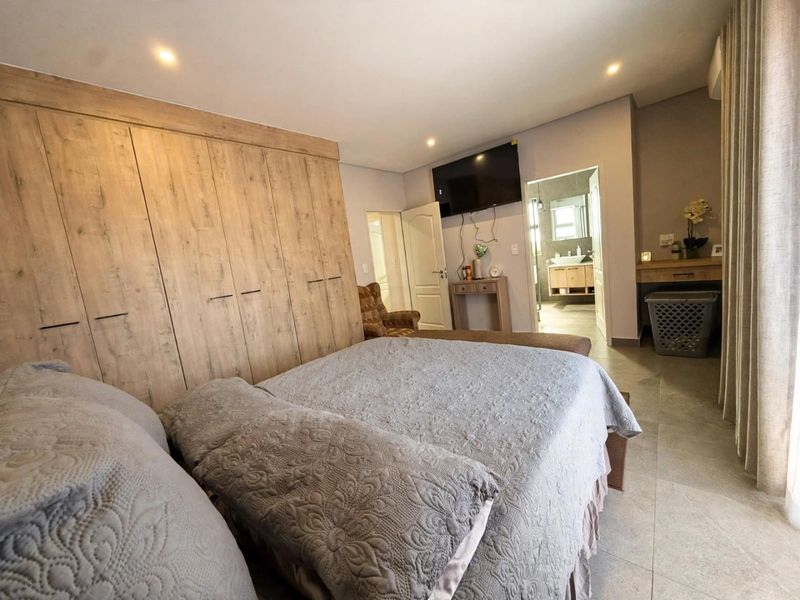 Spacious bedroom featuring extensive built-in wooden cabinetry, tiled flooring, recessed lighting, and direct access to an en-suite bathroom.