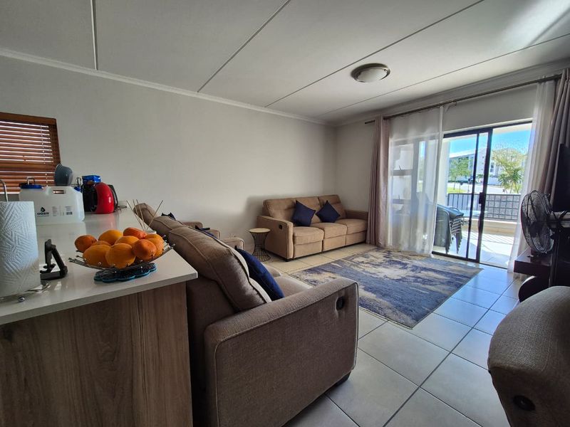 Open plan living area featuring tiled flooring, a kitchen island, and a sliding glass door leading to an outdoor patio space.