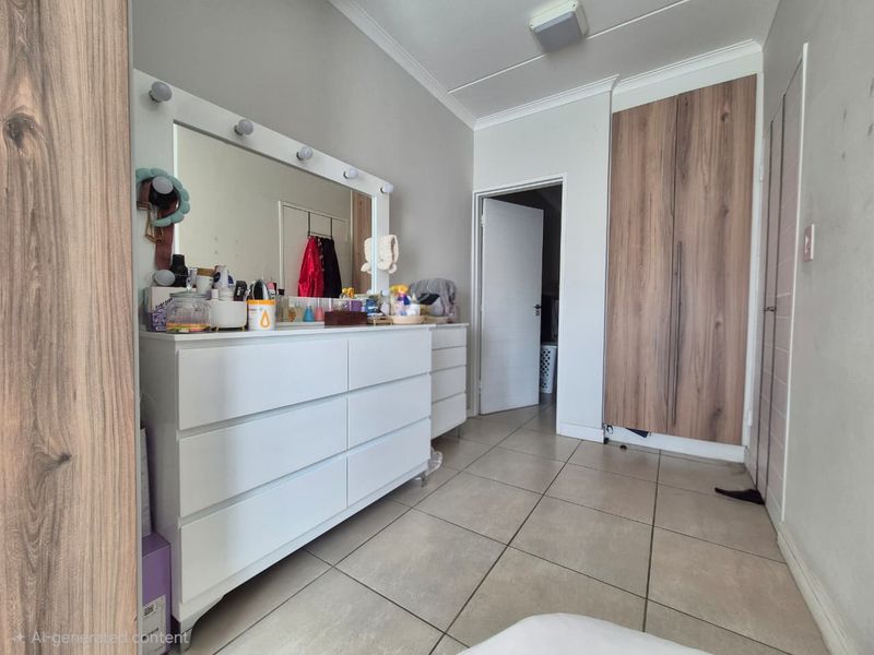 A bedroom featuring tiled flooring, a built-in wardrobe with wood-look finish, and neutral wall tones.