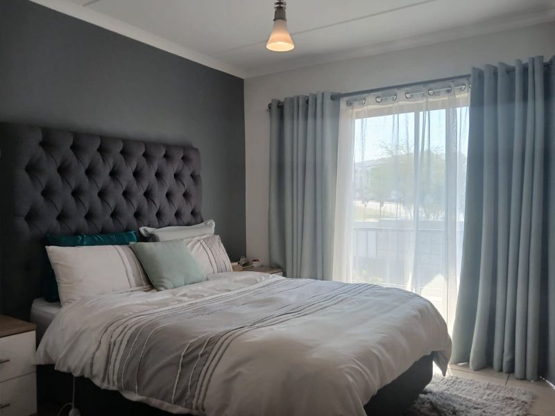 A well-lit bedroom featuring tiled flooring, a feature wall, and a sliding glass door providing access to an outdoor area.