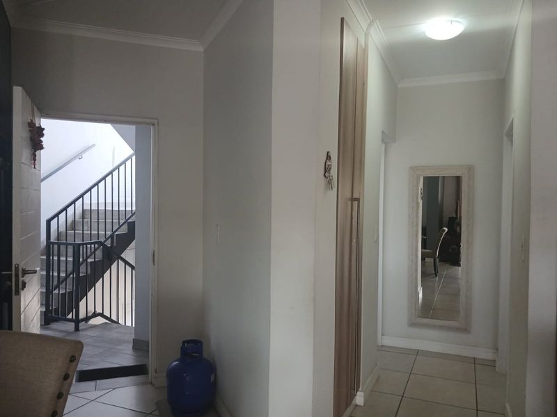 A functional hallway featuring tiled flooring, a built-in cupboard, and access to an external staircase.
