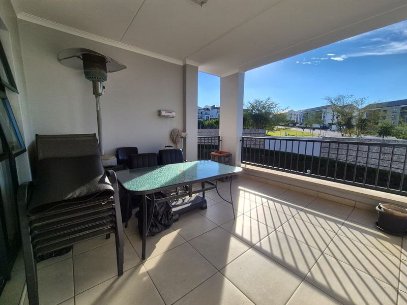 A spacious covered balcony featuring tiled flooring and a metal balustrade, offering an open outdoor area suitable for relaxation and entertaining.