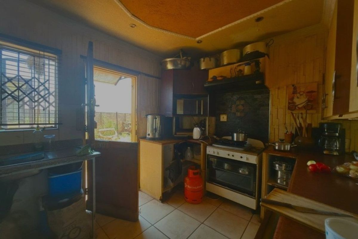 A dated kitchen featuring built-in cabinetry, a gas stove with oven, and direct access to the exterior. The space requires modernization.