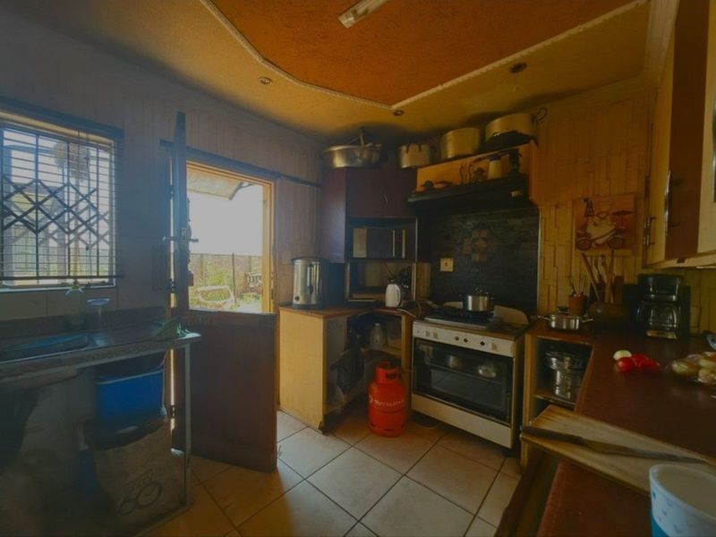 A dated kitchen featuring built-in cabinetry, a gas stove with oven, and direct access to the exterior. The space requires modernization.