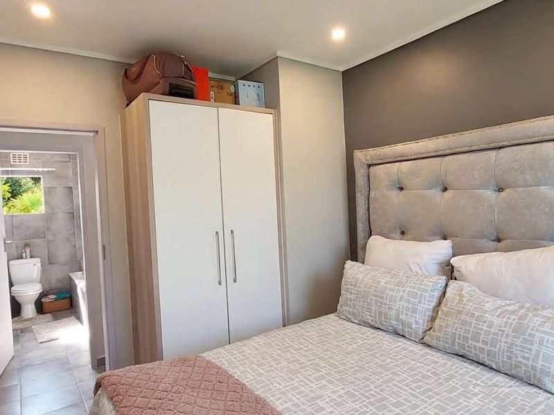 A well-maintained bedroom featuring a built-in wardrobe, recessed lighting, and direct access to an en-suite bathroom.