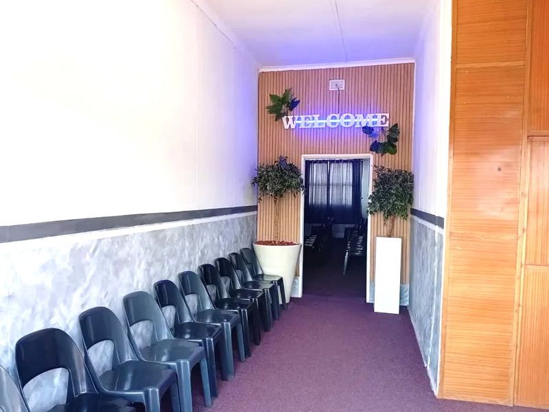 An entrance hallway featuring wood paneling, textured wall finishes, and carpet flooring, leading into an interior space.