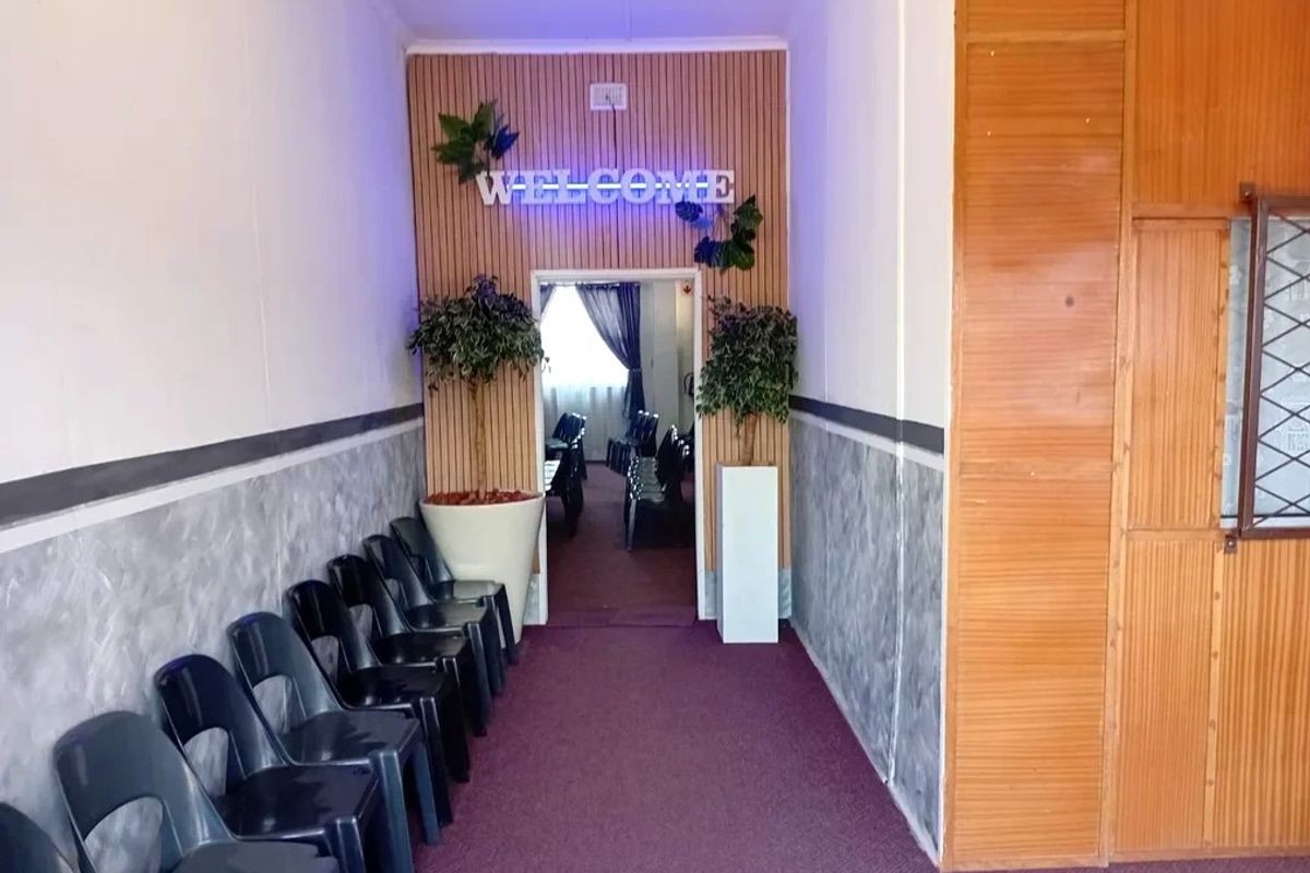 A commercial hallway featuring timber slat wall paneling, textured lower wall finishes, and carpeted flooring leading into an adjacent room.