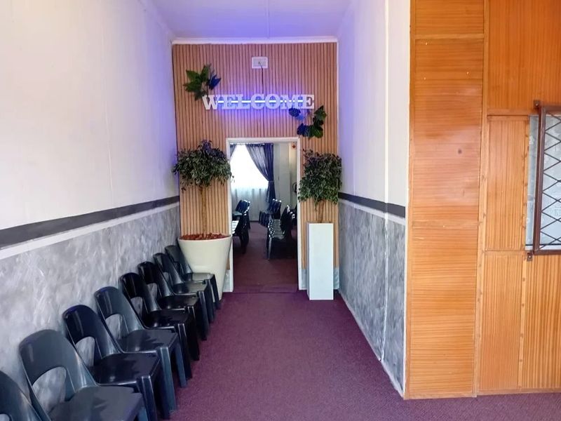 A commercial hallway featuring timber slat wall paneling, textured lower wall finishes, and carpeted flooring leading into an adjacent room.