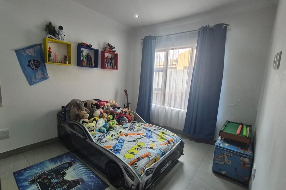A functional bedroom featuring tiled flooring, recessed downlighting, and a large window with curtain tracks.