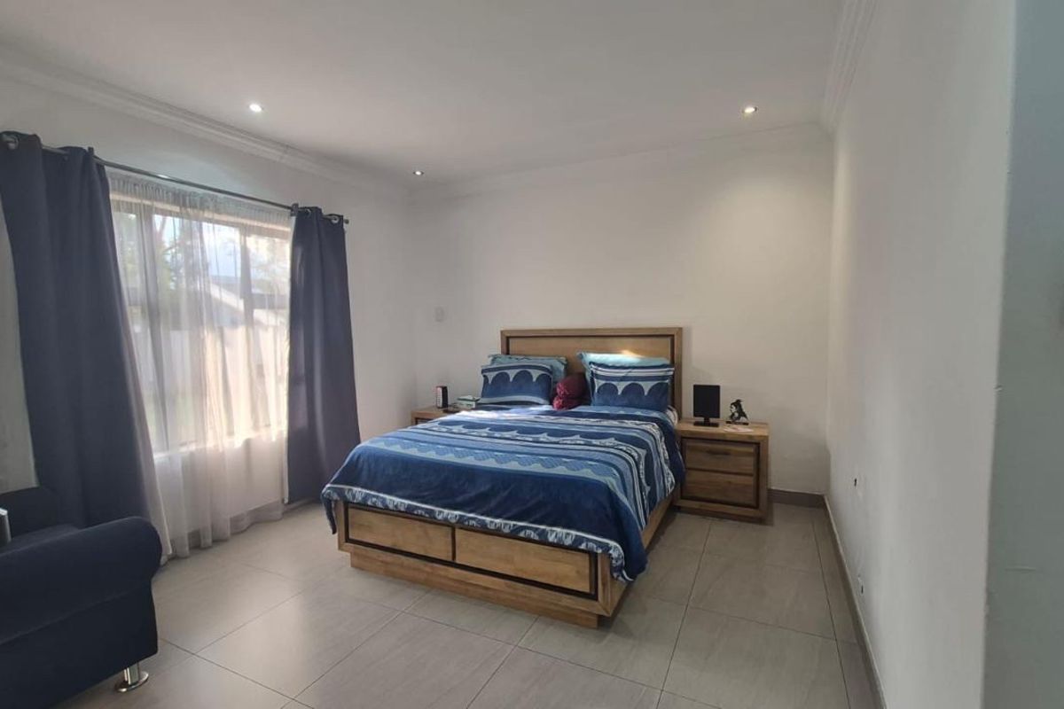 A well-maintained bedroom featuring neutral tiled flooring, recessed downlighting, and coved cornicing, providing a clean and functional living space.