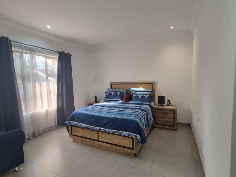 A well-maintained bedroom featuring neutral tiled flooring, recessed downlighting, and coved cornicing, providing a clean and functional living space.