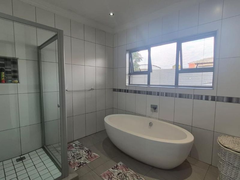 Modern bathroom featuring a freestanding bathtub, a glass-enclosed shower with a built-in niche, and neutral floor-to-ceiling tiling.