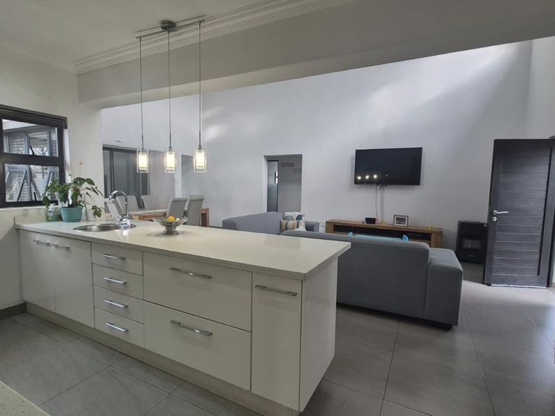 Spacious open-plan living area featuring a modern kitchen with a central island, stone countertops, and seamless flow into the lounge and dining space.