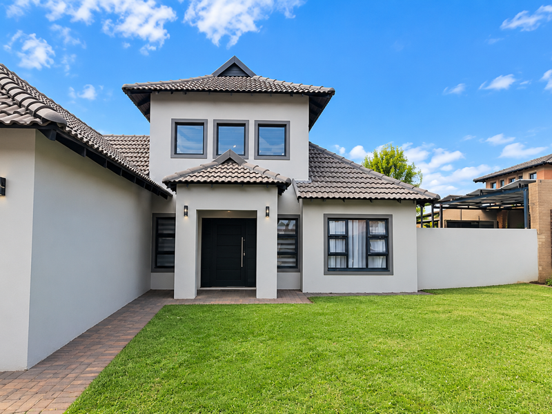 A modern double-storey residential home featuring a tiled roof, paved walkway, and well-maintained front lawn with contemporary exterior finishes.