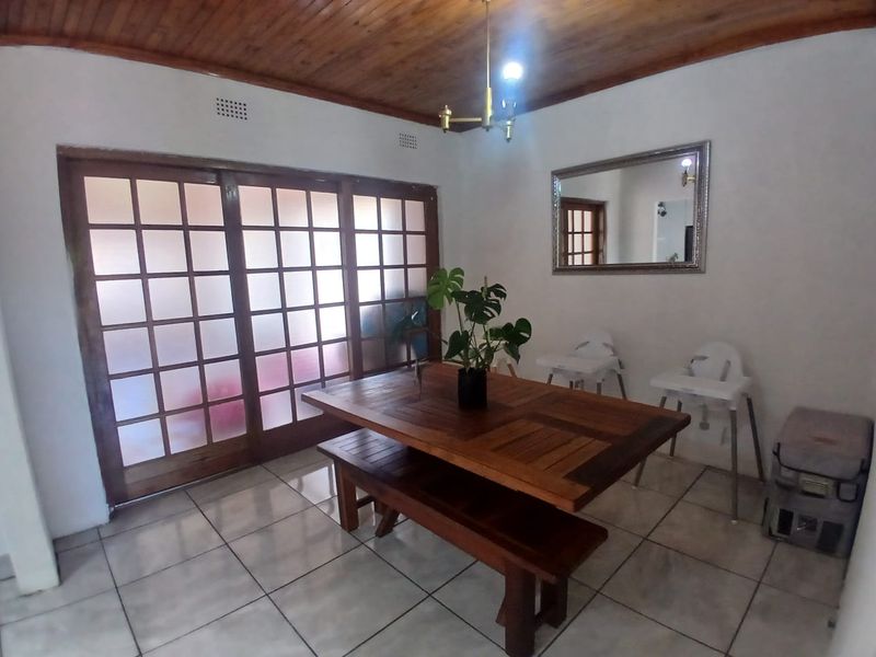 A dining room featuring tiled flooring, a wooden ceiling, and a large sliding glass door providing natural light.