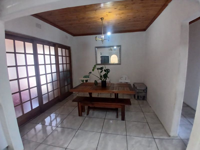 Dining area featuring ceramic floor tiles, a wooden tongue and groove ceiling, and large sliding glass doors providing natural light.