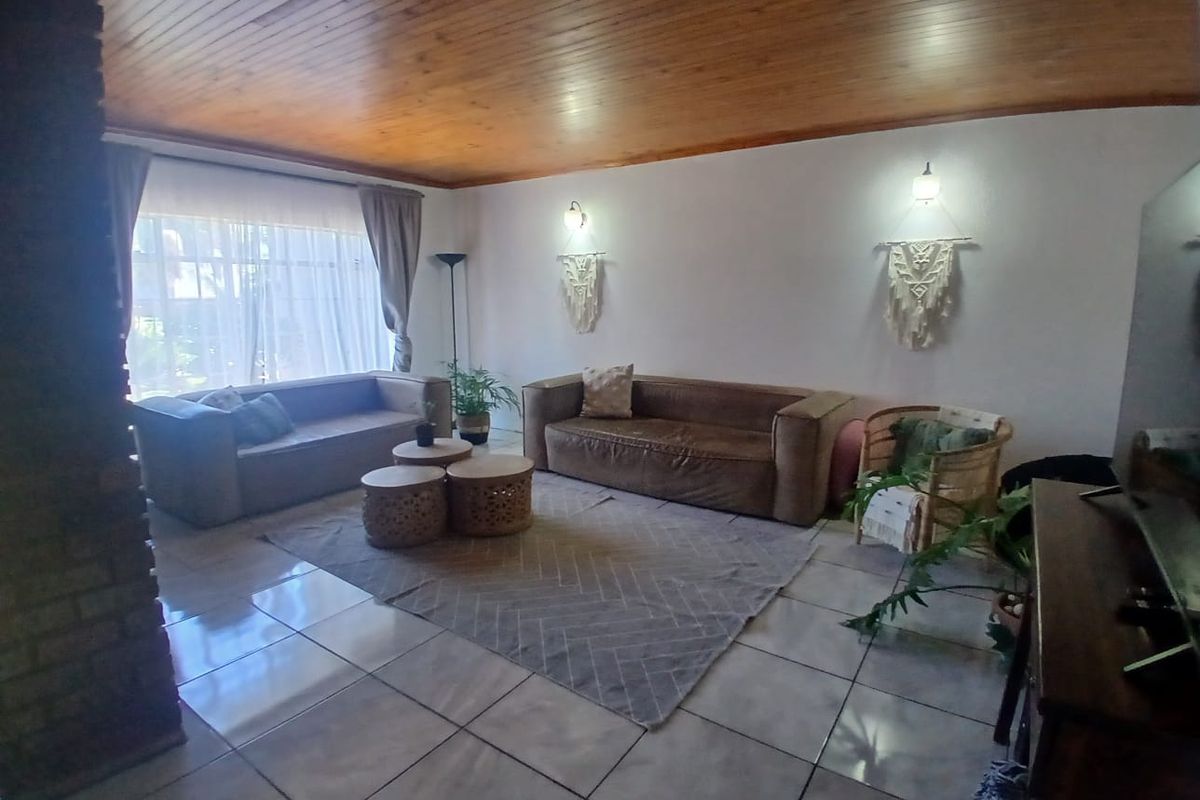 Spacious living room featuring a warm timber tongue and groove ceiling, tiled flooring, and a rustic brick feature pillar.