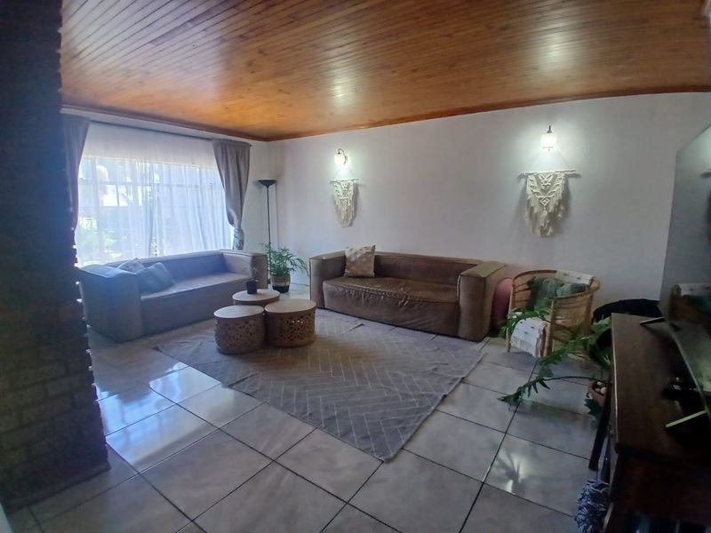 Spacious living room featuring a warm timber tongue and groove ceiling, tiled flooring, and a rustic brick feature pillar.