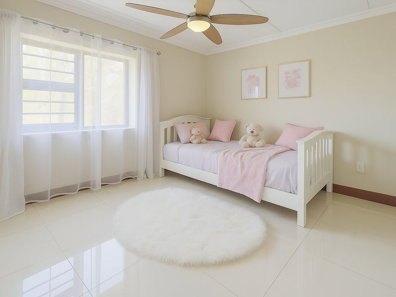 A bright and well-maintained bedroom featuring neutral walls, polished tiled flooring, crown molding, and a modern ceiling fan.