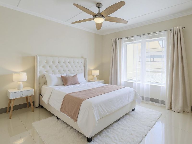 A well-maintained bedroom featuring neutral tones, tiled flooring, crown molding, and a modern ceiling fan, offering a bright and comfortable living space.