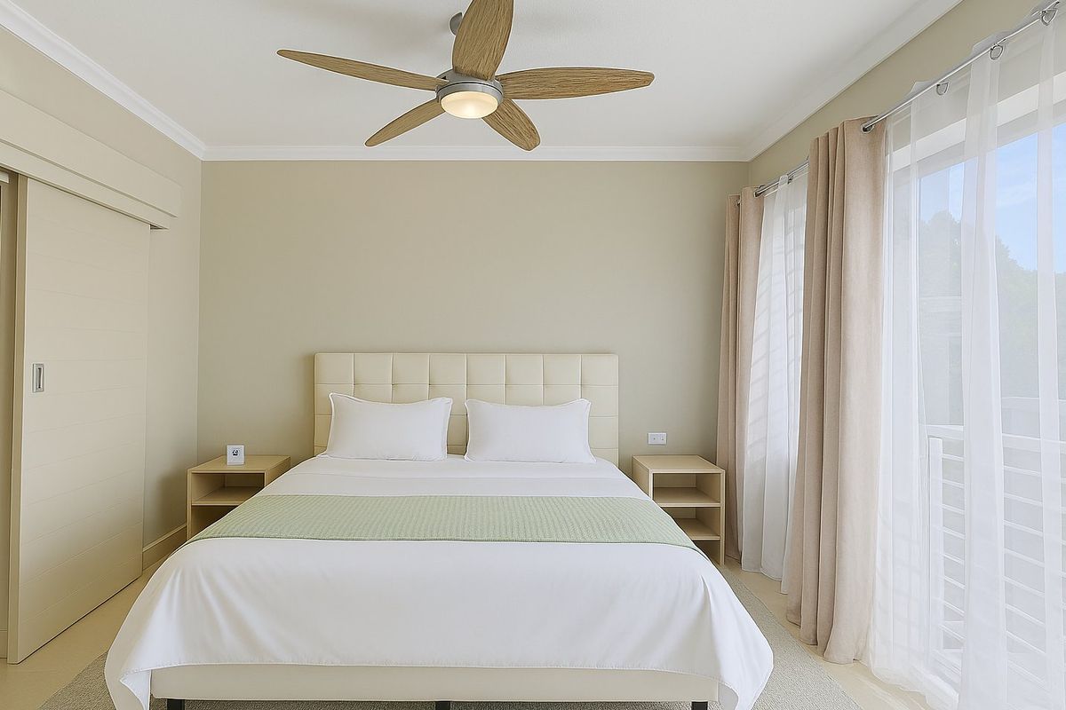 A well-maintained bedroom featuring a modern ceiling fan, neutral wall tones, and a sliding door providing access to an outdoor area.