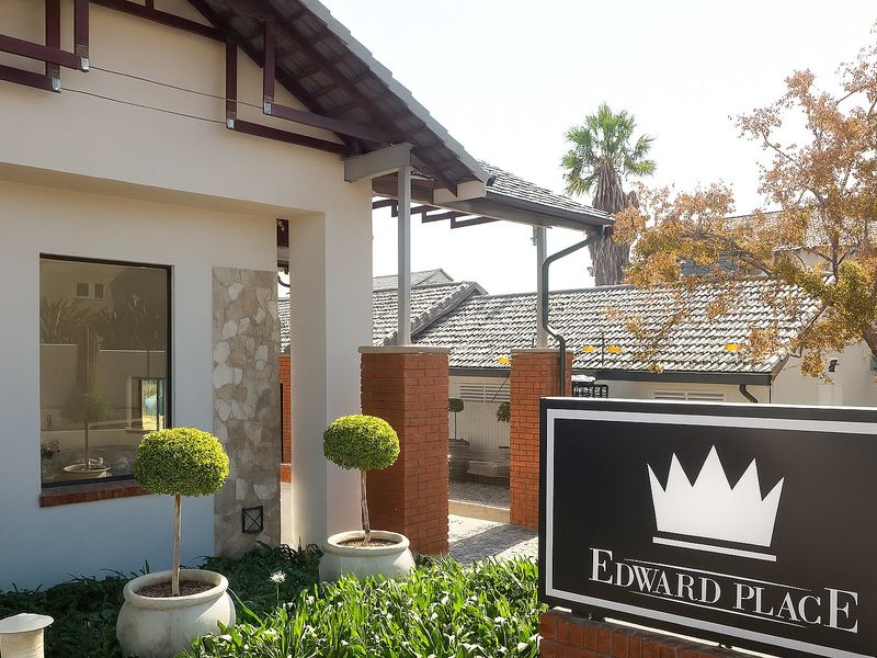 Front entrance view of Edward Place featuring a covered walkway, brick pillars, and stone cladding accents.