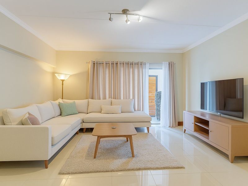 A bright and well-maintained living room featuring polished tiled flooring, coving, and a sliding glass door providing access to an outdoor area.