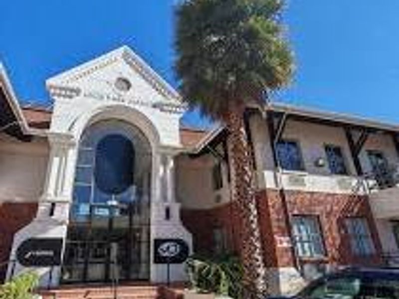 Front elevation of a commercial building featuring a prominent arched entrance, brick masonry, and glass storefront elements.