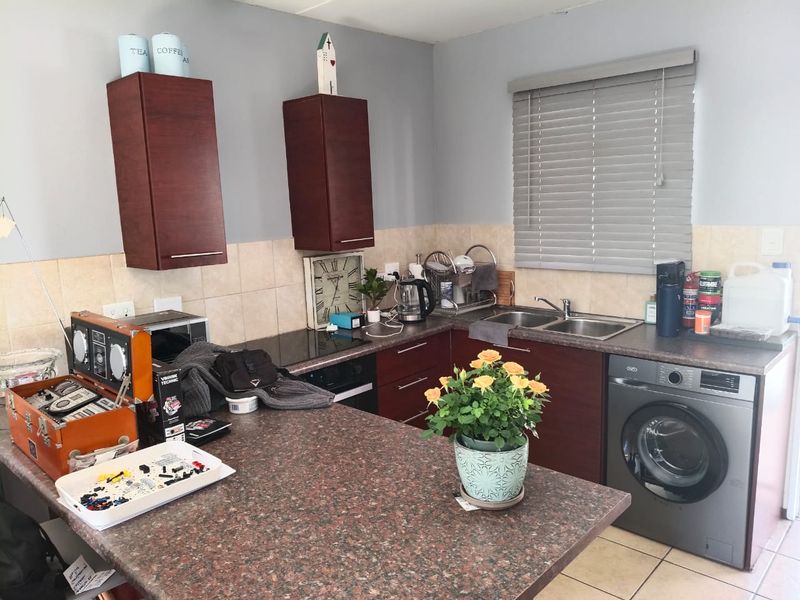 A functional kitchen featuring dark wood cabinetry, laminate countertops, a double basin sink, and a built-in oven with a tiled backsplash.