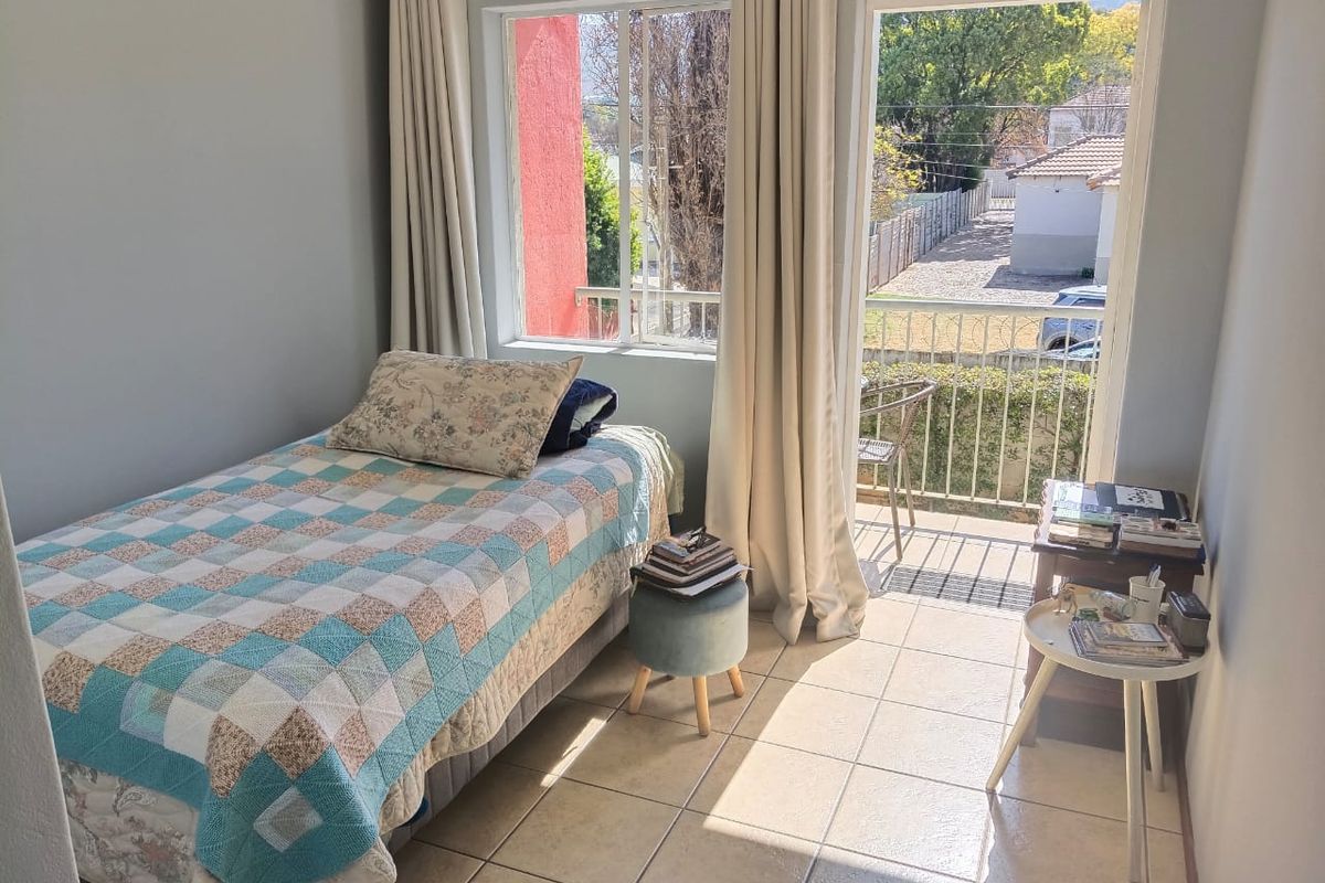 A bright bedroom featuring tiled flooring and direct access to a private balcony through a sliding glass door, offering natural light and outdoor views.