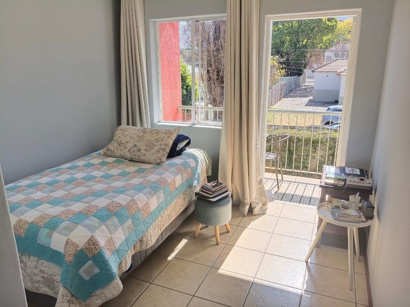 A bright bedroom featuring tiled flooring and direct access to a private balcony through a sliding glass door, offering natural light and outdoor views.