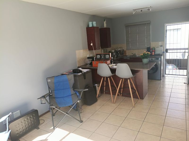 Open plan kitchen area featuring tiled flooring, built-in cabinetry, and direct access to an outdoor space through a security gate.