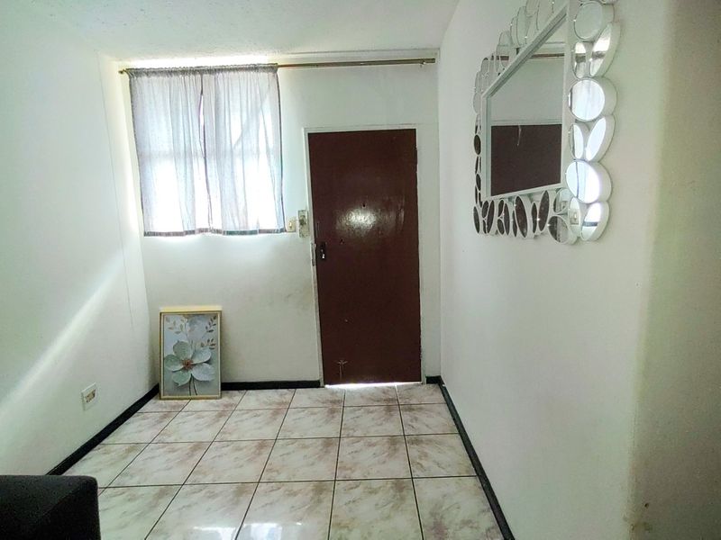 A simple entry area featuring tiled flooring and a single access door, providing a functional transition space for the home.
