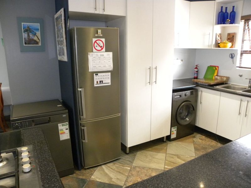 Functional kitchen featuring built-in cabinetry, granite countertops, a stainless steel sink, and a built-in hob with tiled flooring throughout.
