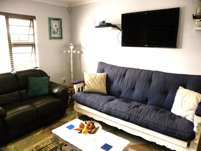 A comfortable living room featuring tiled flooring, louvered windows, and decorative coving, providing a functional and inviting space for relaxation.