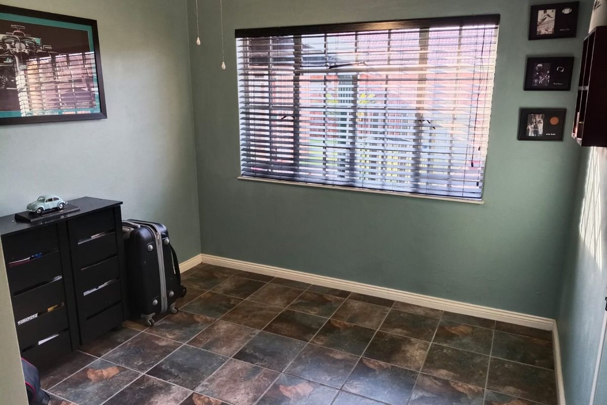 A simple bedroom featuring tiled flooring and venetian blinds, offering a neutral space ready for personalization.
