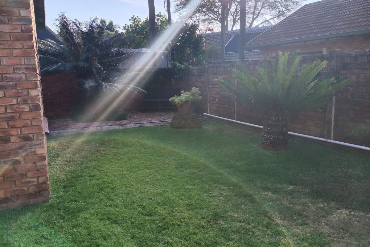 A private rear garden featuring a lawn, paved patio area, and brick boundary walls.
