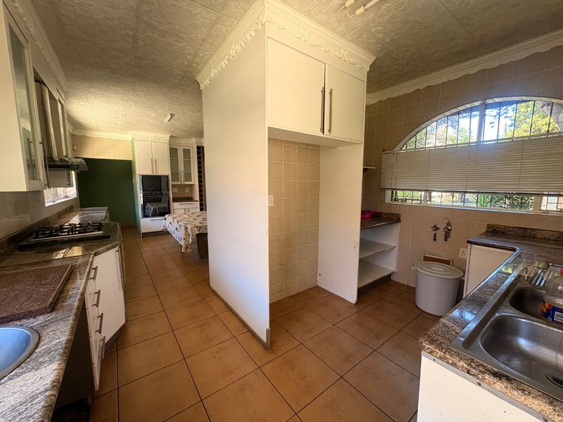 Spacious kitchen featuring granite countertops, built-in oven and hob, and ample cabinetry, offering significant potential for a modern renovation.